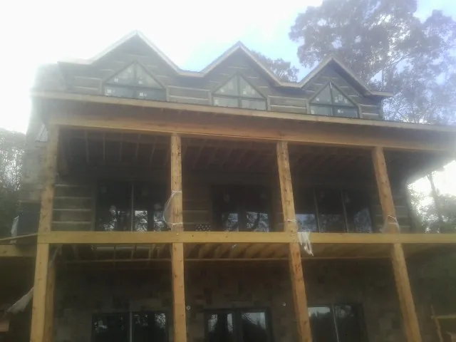 Dormers and porch framing on a large log home under construction — Roof Coating work by our crew in Brunson