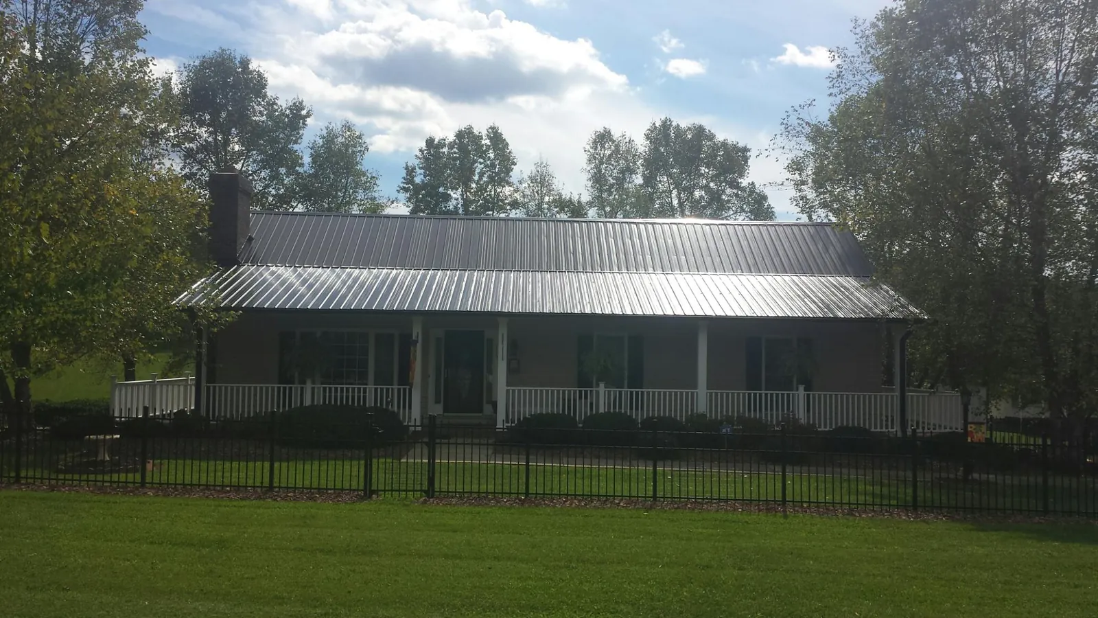 Gray metal roof on a brick ranch with a full width front porch — Gutter Guard Installation work by our crew in Brunson